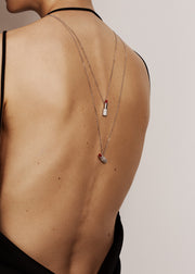 Model wearing lipstick shape pendant on long white gold chain against white background